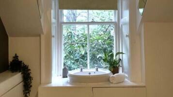 A bathroom with a window, a sink, and a towel.