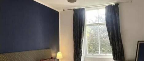 Una habitación de hotel con dos camas, una ventana con cortinas, una lámpara y una luz en el techo.