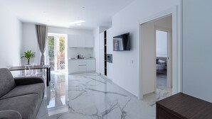 A modern living room with a sofa, a coffee table, and a TV mounted on the wall. - Alberti Apartments Historical Center Trapani (Trapani)