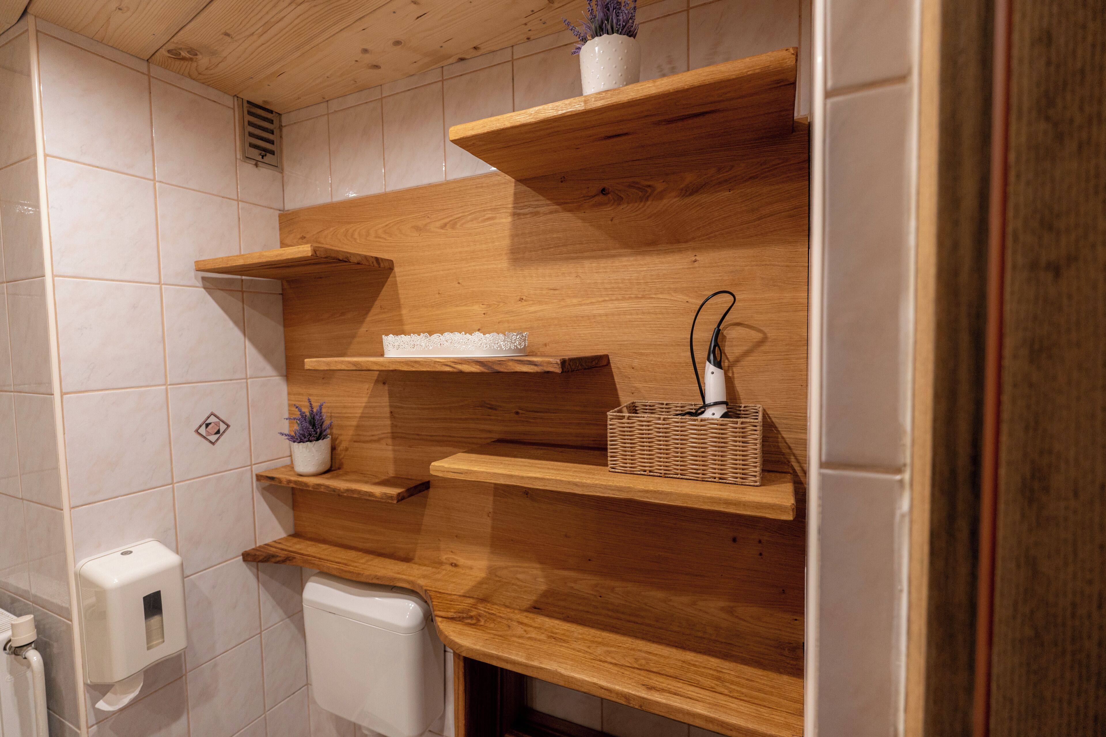 Une salle de bain avec des étagères en bois, des toilettes et un sèche-mains.