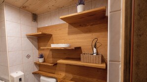 Un baño con estantes de madera, un inodoro y un secador de manos.