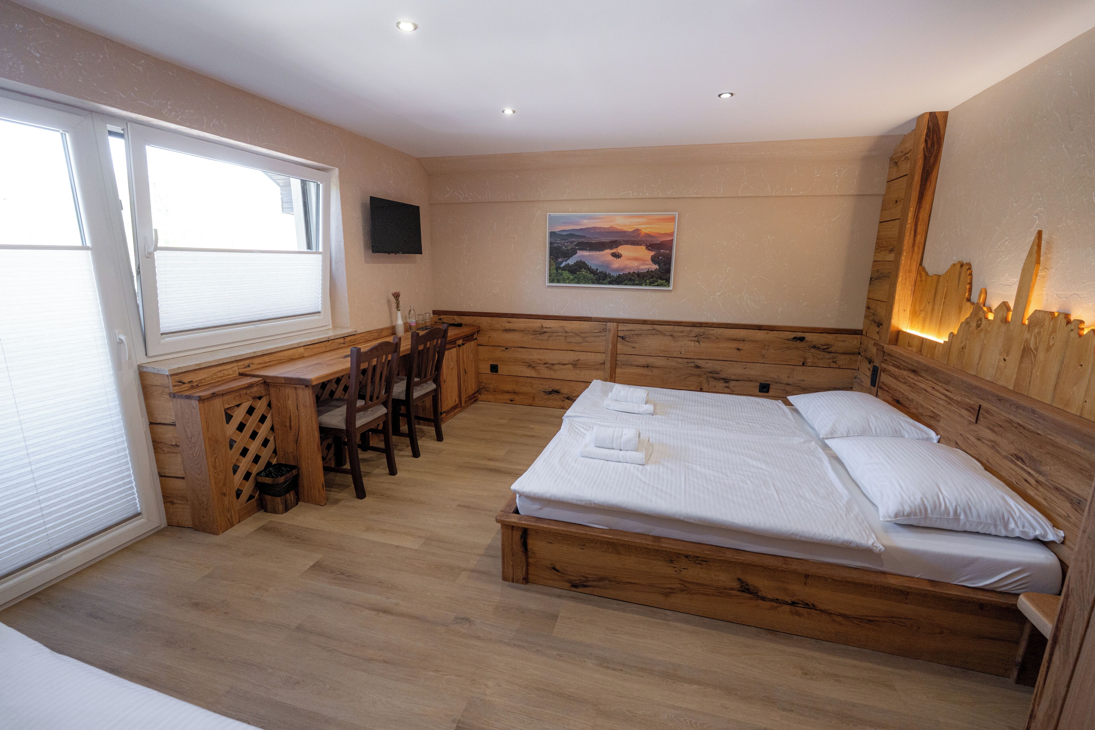 A bedroom with a wooden bed, a desk, and a chair.