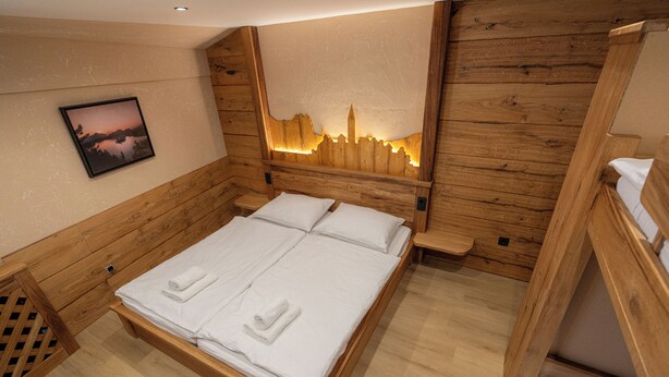 Una habitación de madera con una cama, una mesita de noche y un cuadro colgado en la pared.
