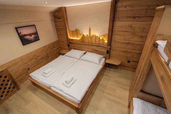 Una habitación de madera con una cama, una mesita de noche y un cuadro colgado en la pared.
