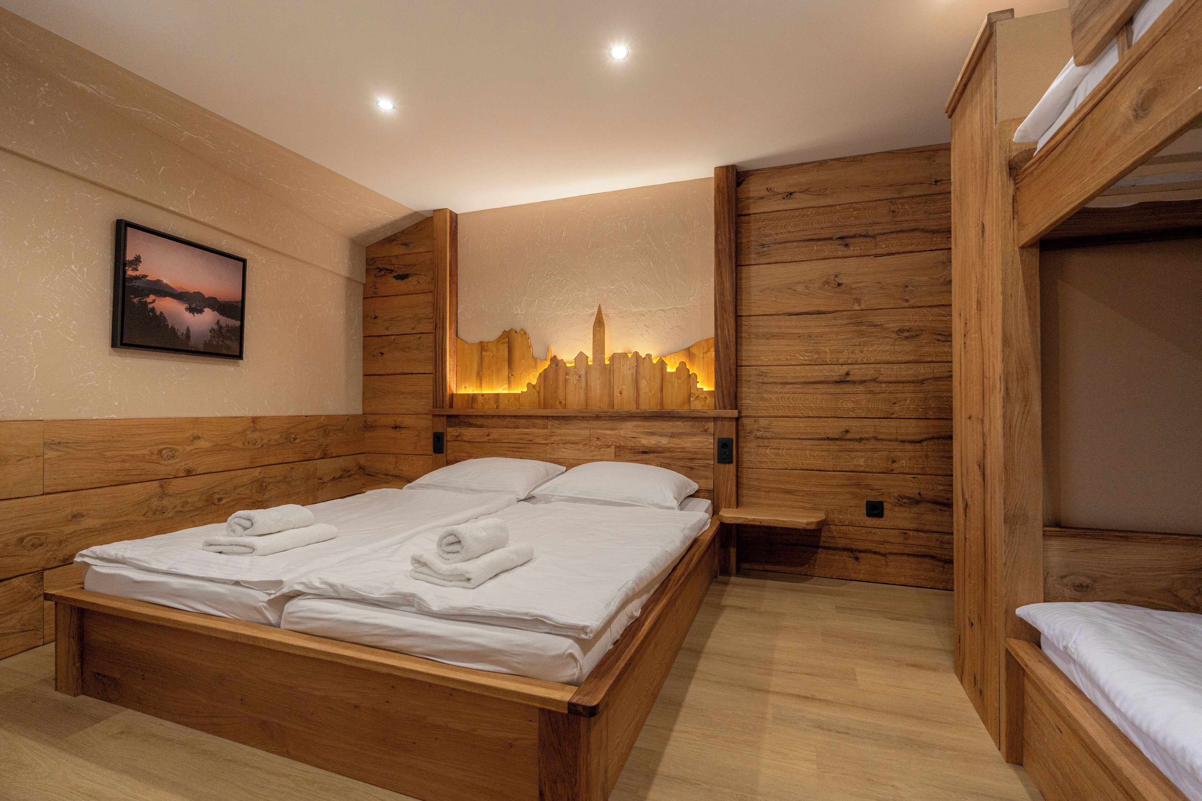 A wooden room with a bed, a bench, and a wall-mounted light fixture.