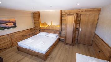 A wooden-framed bedroom with a bed, a bench, and a wardrobe.