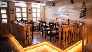 Una zona de bar con mobiliario de madera, suelo de piedra y un mural en la pared.