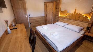 A wooden room with a bed, a desk, and a wardrobe.