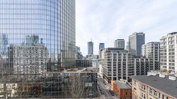 Stadsbeeld met moderne wolkenkrabbers, een combinatie van glazen en betonnen architectuur, en een heldere lucht.