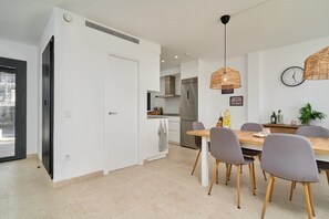 A modern kitchen with a dining area, featuring a large wooden table, grey chairs, and a hanging light fixture. - Holiday Home 'Exclusive Getaway – Ocean View' with Sea View, Wi-Fi and Air Conditioning (Torrox)