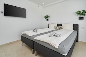 A modern bedroom with a bed, bedside tables, a TV, and two potted plants. - Holiday Home 'Exclusive Getaway – Ocean View' with Sea View, Wi-Fi and Air Conditioning (Torrox)