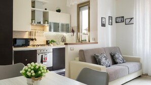 A compact living space with a kitchenette, a dining area, and a seating area with a sofa and chairs. - Bilocale moderno a Bollate vicino a Fieramilano e Milano Ice Park (Bollate)
