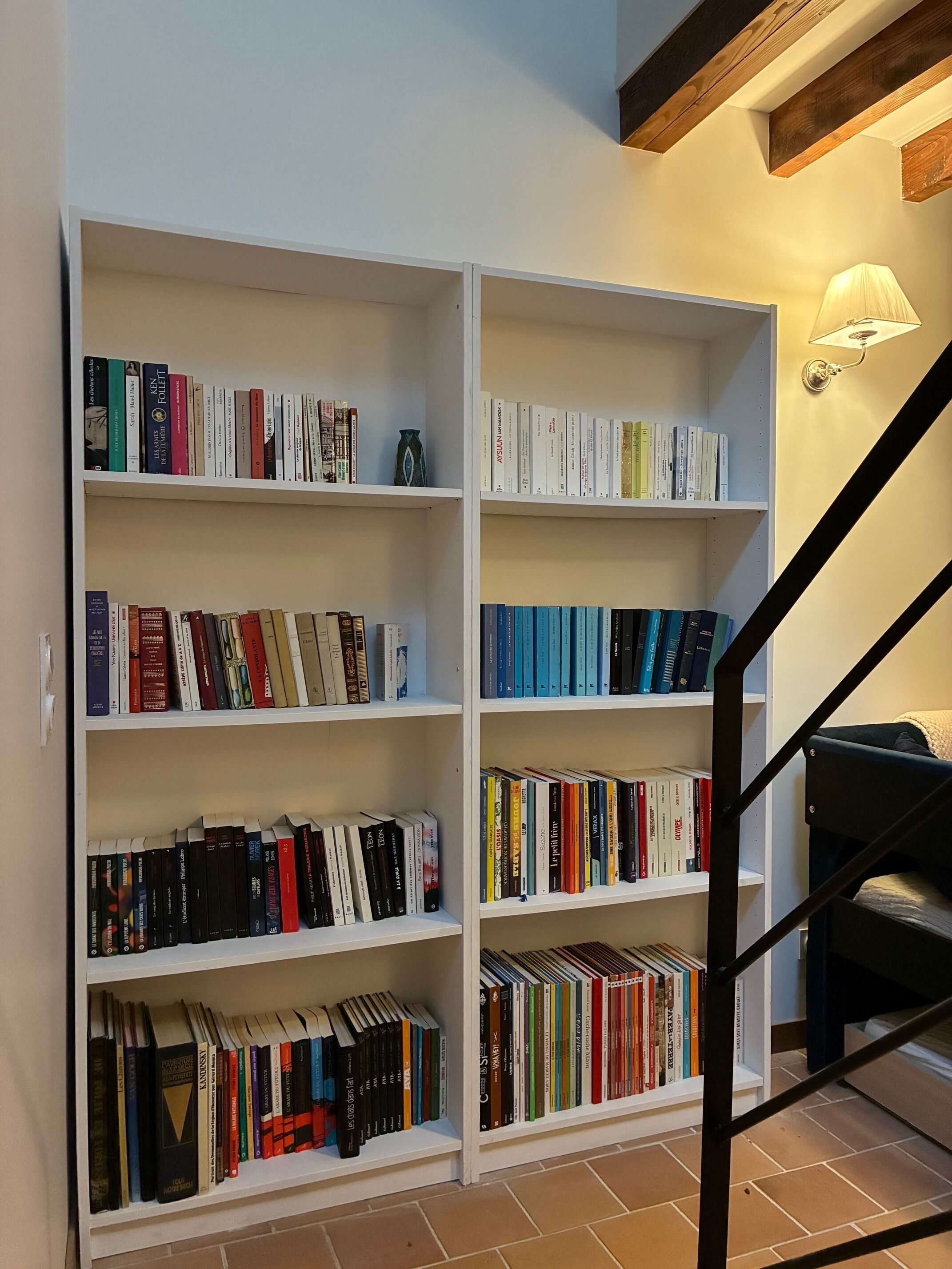 Une bibliothèque dotée de nombreuses étagères blanches, toutes remplies de livres.