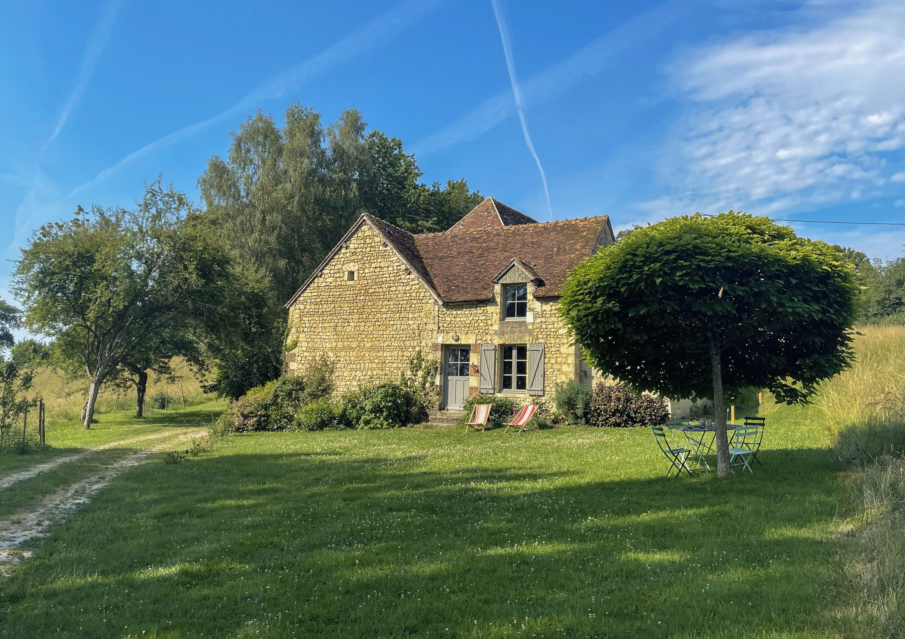A stone house with a sloped roof, a paved driveway, and a well-maintained lawn.
