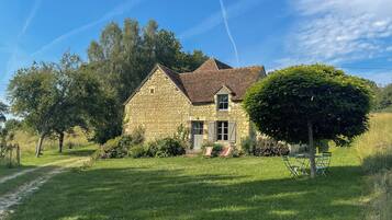 A stone house with a sloped roof, a paved driveway, and a well-maintained lawn.
