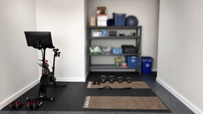 A home gym setup with an exercise bike, kettlebells, and resistance bands on a mat. - Brand new 2-bedroom condo in beautiful New Braunfels (New Braunfels)