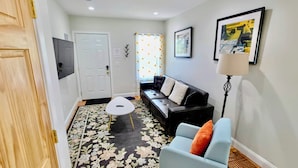 Un salon comprenant un canapé, un fauteuil, une table basse, une lampe et une porte.