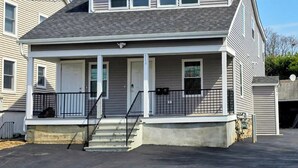 Une maison à deux étages avec un porche à l’avant, un garage et une allée.
