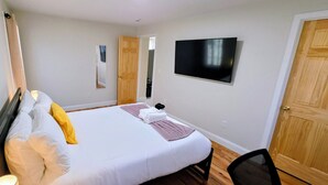 Une chambre d’hôtel avec un lit, une télévision, un miroir et une porte en bois.