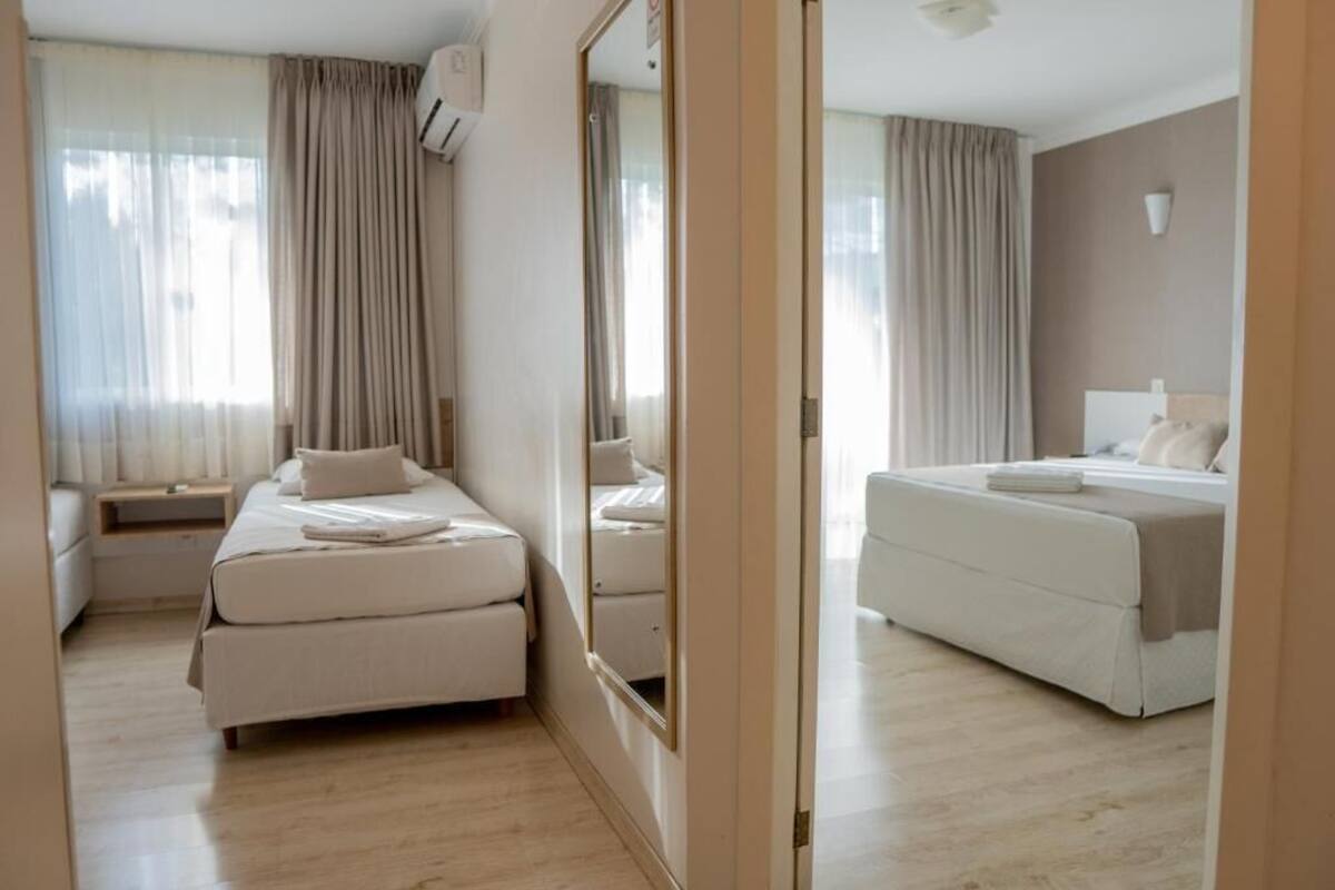 A hotel room with a large bed, a smaller bed, a nightstand, and a mirror.