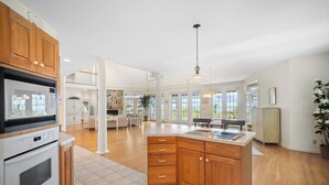 A spacious kitchen with wooden cabinets, a central island, and a large window providing natural light. - Ocean View, Golf Cart Included, Club Cards Available - 8 River Club (Fripp Island)