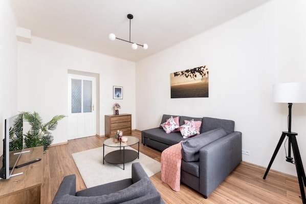 A modern living room with a grey sofa, a coffee table, a lamp, and a painting on the wall. - Malila Apartments Rynek Dębnicki 8 (Kraków)