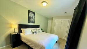 Une chambre à coucher avec un lit, une table de chevet, une lampe et un tableau au mur.