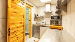 Une cuisine avec une porte en bois, des appareils électroménagers en acier inoxydable et un plan de travail en marbre.