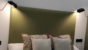 A modern hotel room with a bed, two bedside lamps, a round side table, and a green accent wall. - Apartamentos Ritual Casablanca (Torremolinos)