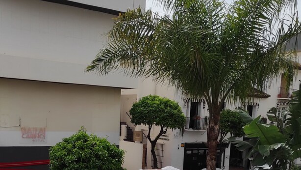 A patio with a round table and white chairs, surrounded by a white wall with a red and white striped pattern. - Apartamentos Ritual Casablanca (Torremolinos)
