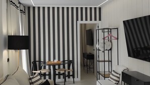 A modern living room with a sofa, a round coffee table, a TV mounted on the wall, and a striped wall design. - Apartamentos Ritual Casablanca (Torremolinos)