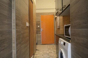 A narrow hallway with a washing machine and a television on a stand. - Stylish 1BR Long Stay | Close to AKH (Vienna)