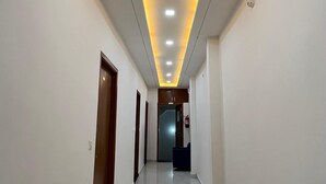 A hallway with a modern ceiling design featuring recessed lighting and a central light fixture. - Hotel Golden Palace (Agra)