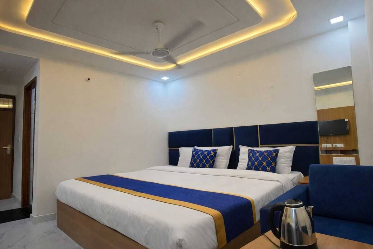 A hotel room with a bed, a coffee table, a sofa, a ceiling fan, and a TV mounted on the wall.
