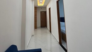 A hotel hallway with a blue sofa, a wooden door, and a ceiling with recessed lighting. - Hotel Golden Palace (Agra)