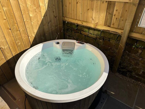 A hot tub with a control panel, surrounded by wooden walls and a stone base. - Foundry Farm Arch- pod Inspired Home (Hexham)