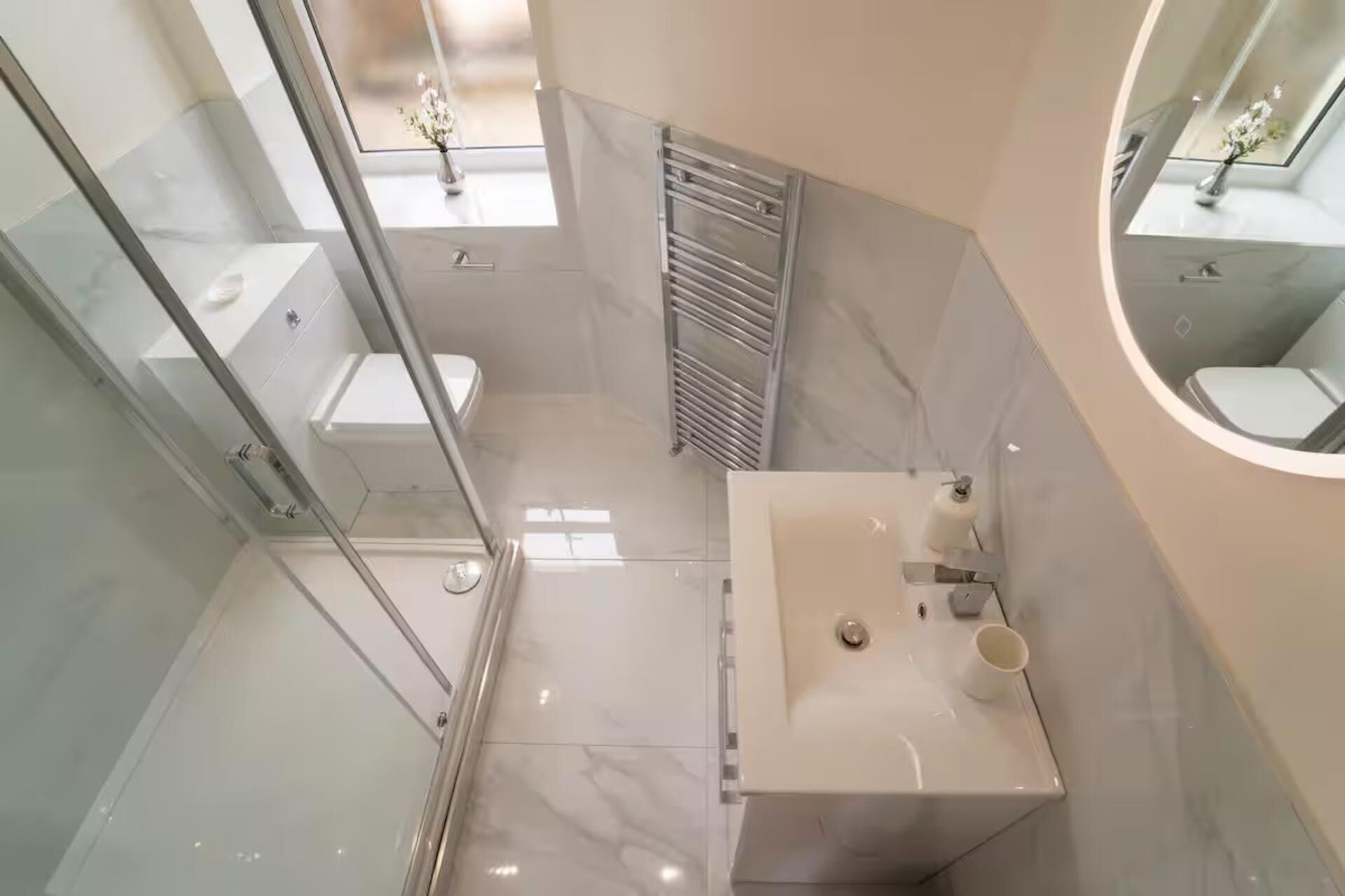 Un baño moderno con cabina de ducha de vidrio, tocador con lavamanos y un inodoro.