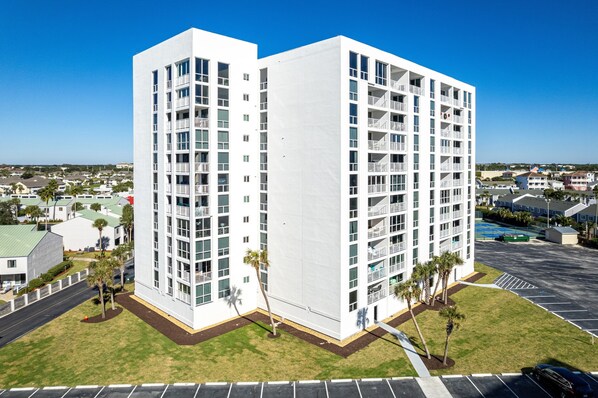 A modern multi-story building with balconies, a parking lot, and a clear view of the surrounding neighborhood. - Gulf Front Shoreline Towers 1046 3 BR with Beach Service for 4! (Destin)