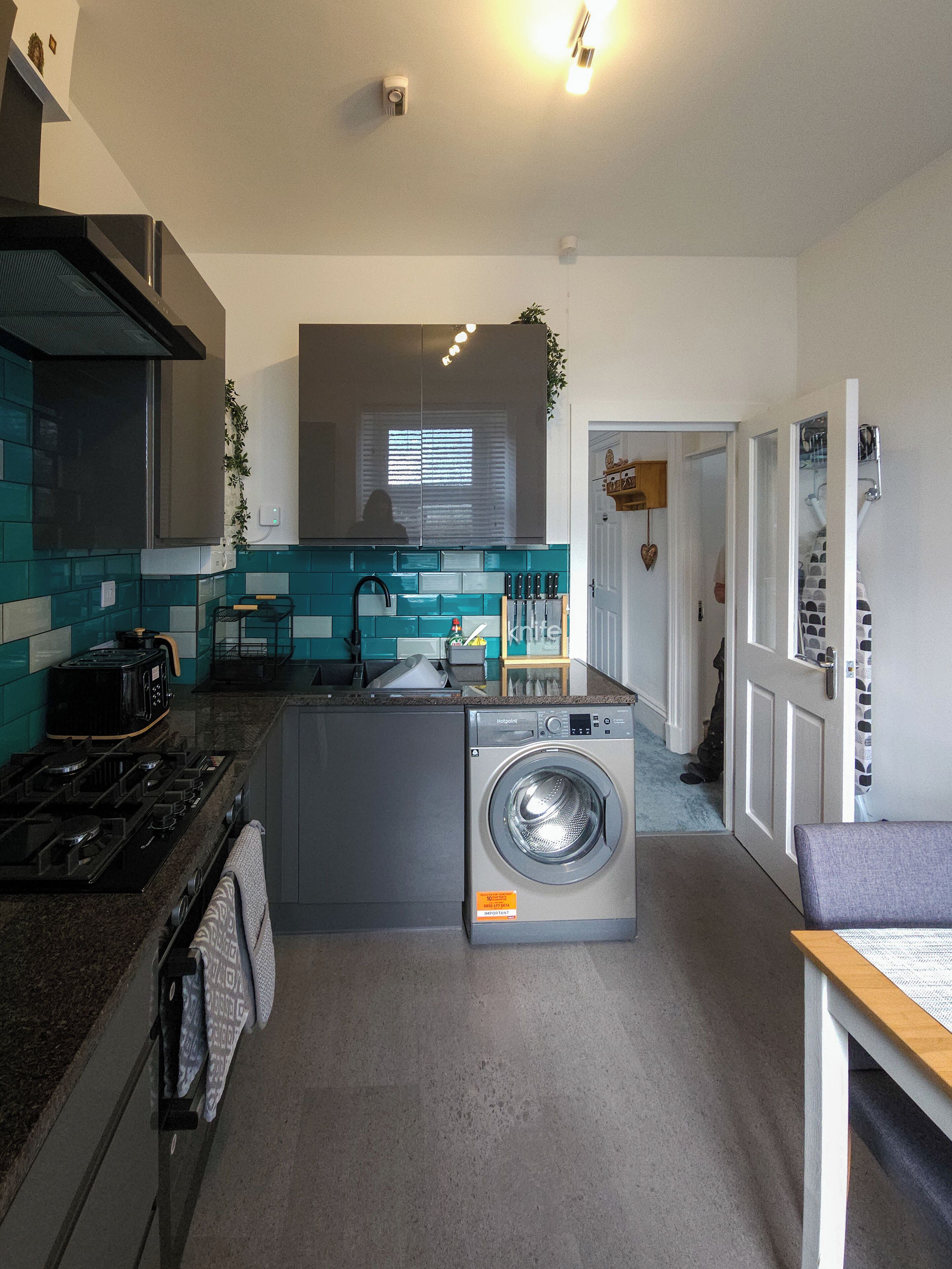 Une cuisine compacte équipée d’un lave-linge intégré, d’une cuisinière et d’un évier.