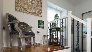 A staircase with a wooden finish, a decorative chair with a floral pattern, and a wall-mounted artwork. - Stunning, large, 2 king sized bedroom apartment. (Glasgow)