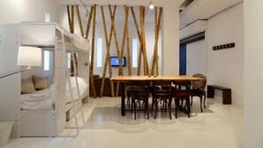 A compact room with a bunk bed, a dining table with chairs, and a bamboo wall divider. - Super 8 (Athens)