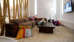 A modern living room with a brown sofa, colorful cushions, a dark coffee table, and a TV mounted on the wall. - Super 8 (Athens)