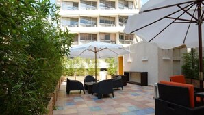An outdoor patio area with tiled flooring, outdoor furniture, and umbrellas. - Super 8 (Athens)