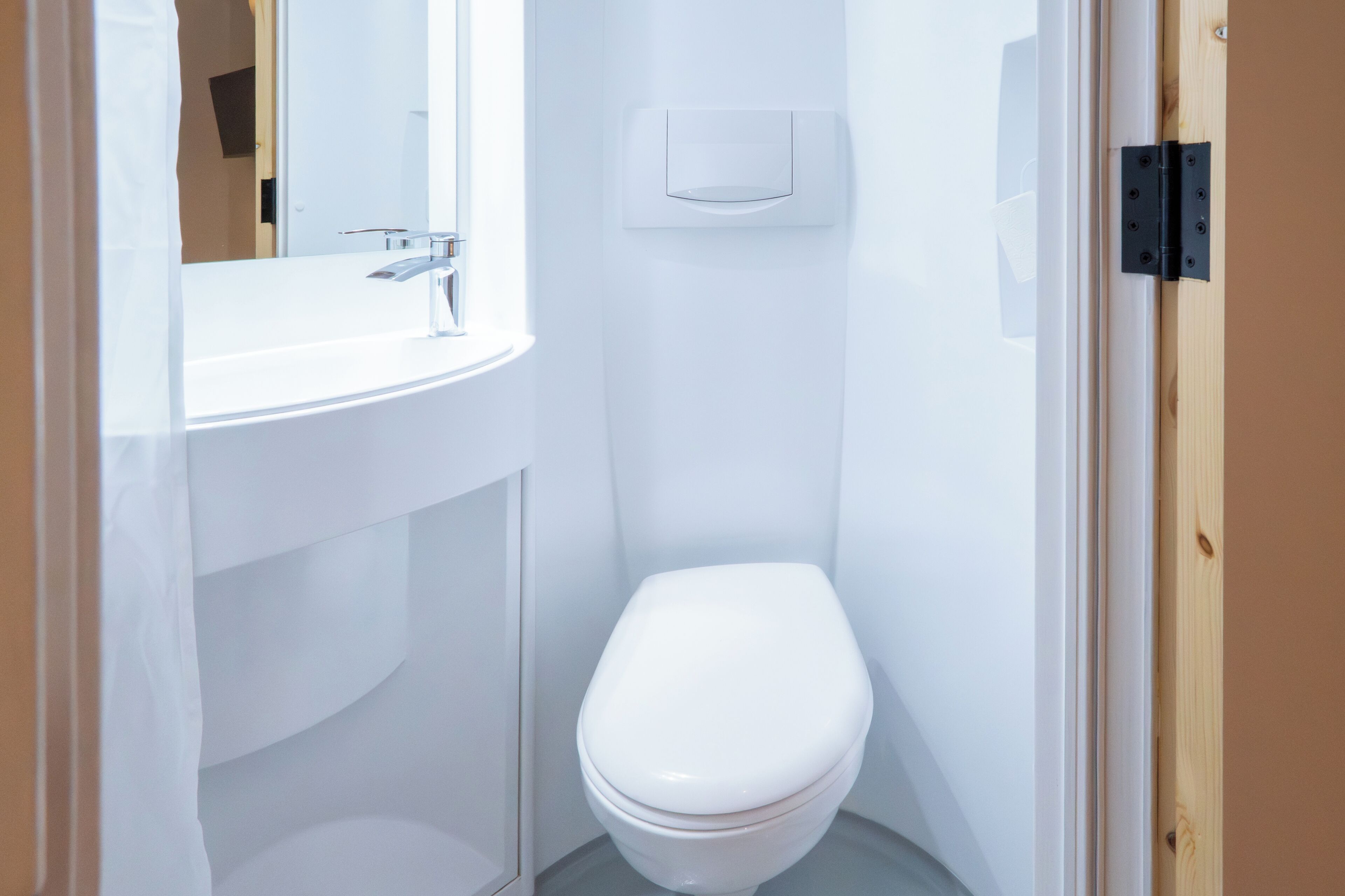 Un baño pequeño y blanco con un inodoro, un lavabo y un espejo.