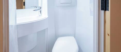 A small, white bathroom with a toilet, a sink, and a mirror.