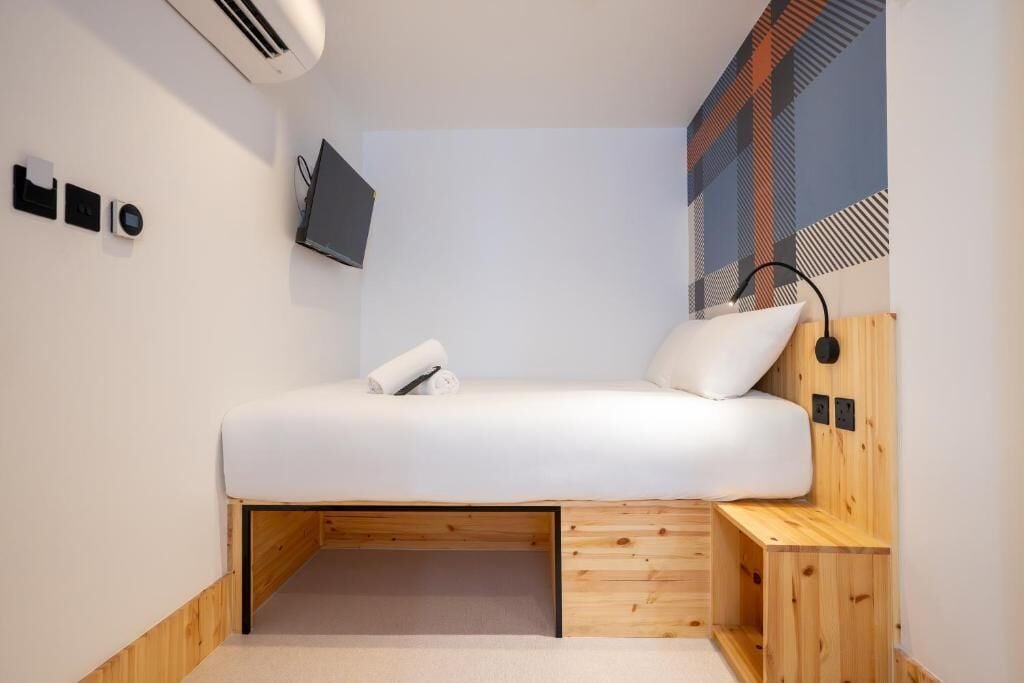 Une chambre moderne avec un lit, un bureau et un téléviseur fixé au mur.