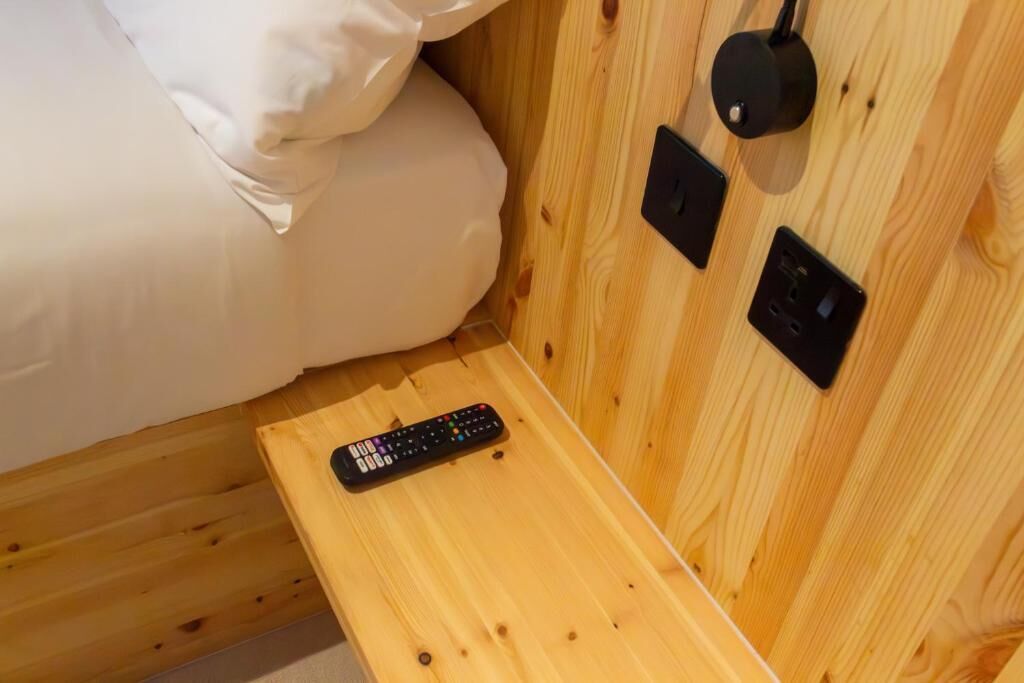 A wooden bunk bed with a remote control on the lower bunk.