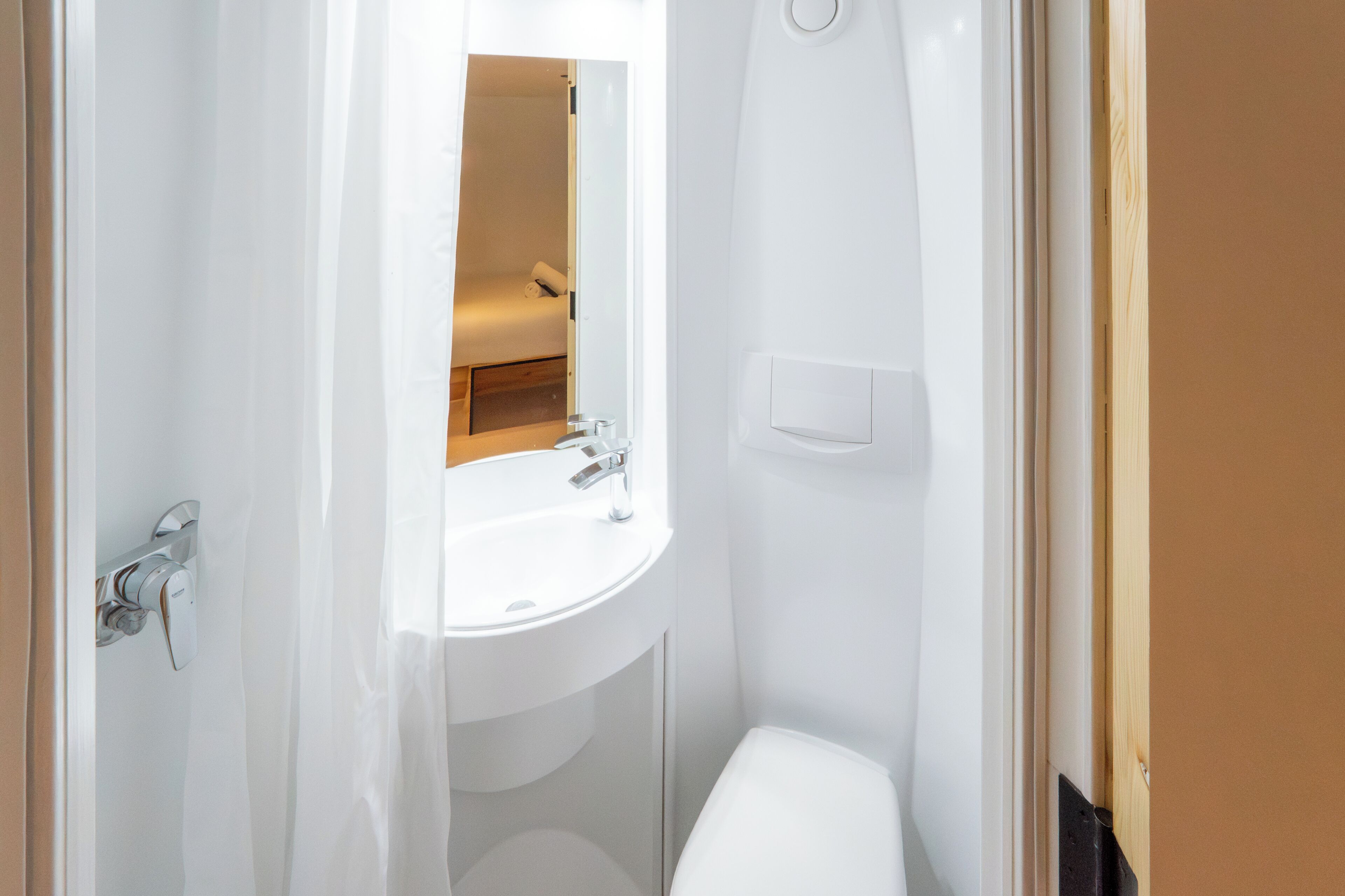 A small, white bathroom with a sink, mirror, and toilet.