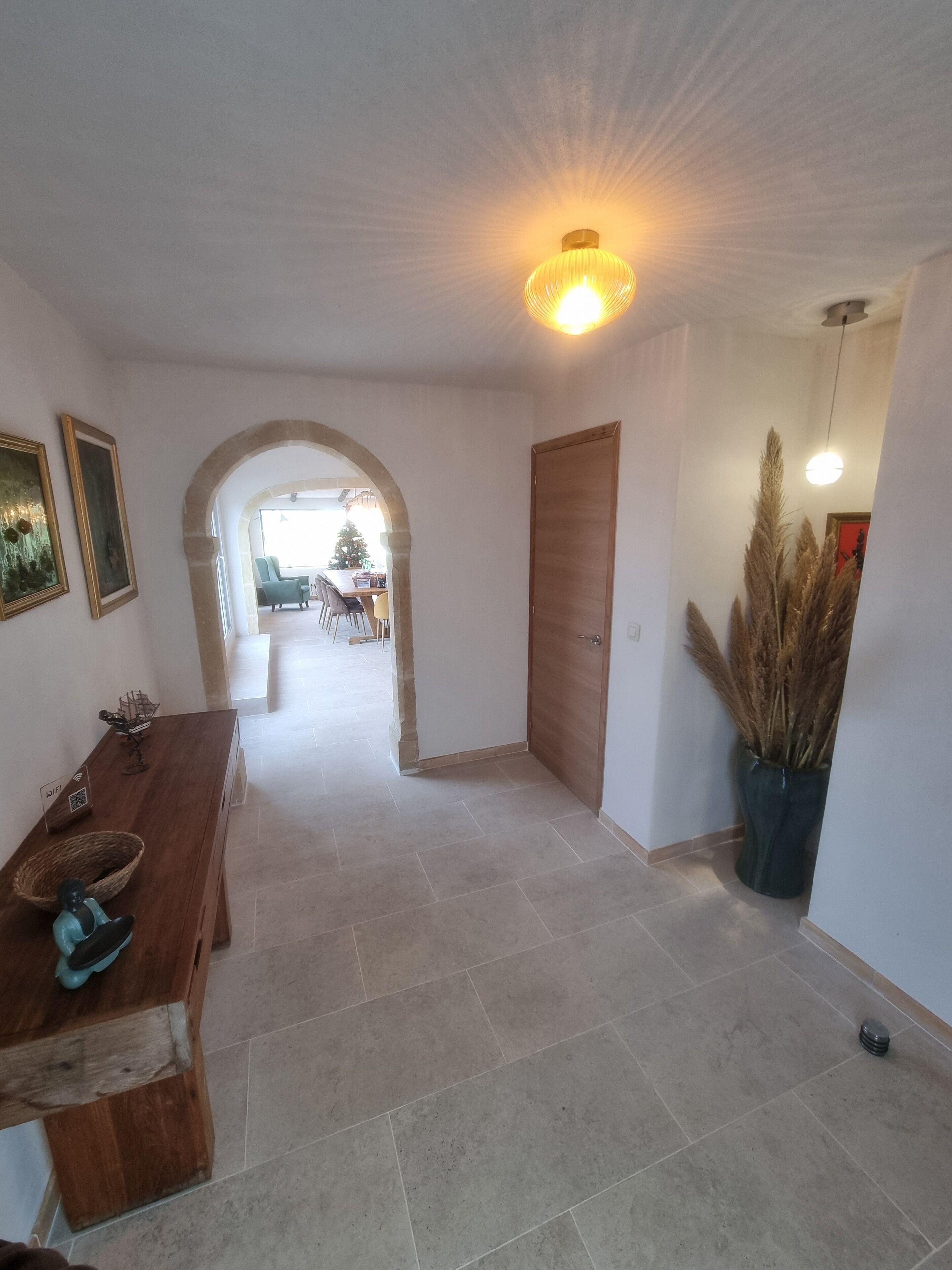 A spacious hallway with a wooden bench, a potted plant, and a door leading to another room.