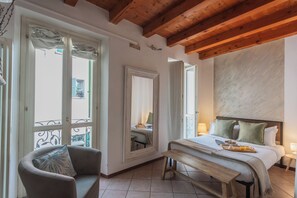 Une chambre à coucher avec un lit, un banc, une chaise et une grande fenêtre.
